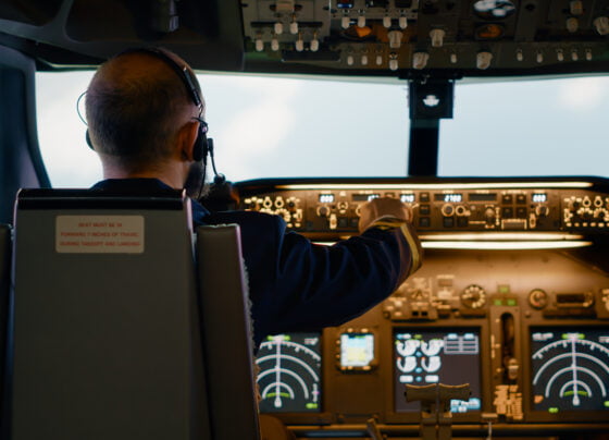 male airline captain fixing altitude longitude buttons using dashboard navigation command control panel flying airplane with aircrew radar compass power engine windscreen